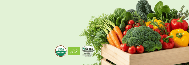 A wooden crate filled with fresh vegetables including broccoli, carrots, tomatoes, peppers, and leafy greens on a pale green background, with USDA Organic and Ecocert certification logos on the left.